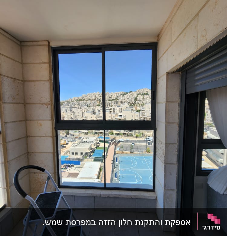 חלון אלומיניום עם נוף עירוני וסולם קטן